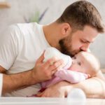 father feeding baby bottle