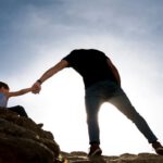 father son help rocks mountain