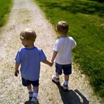 boys holding hands walking away down a path