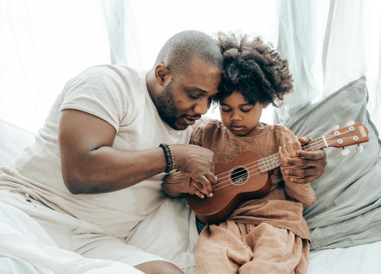 be present dad teaches child to play ukulele