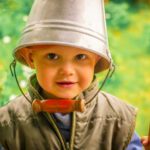 child with bucket on head