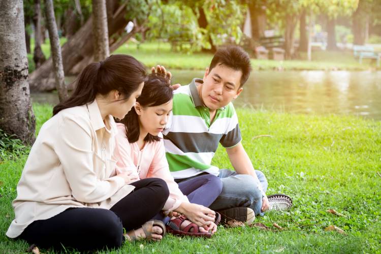 co-parenting Asian mom and dad console daughter in park