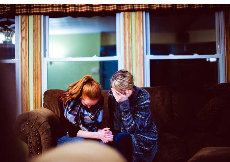 man woman crying on couch comforting each other