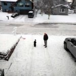 father son stand in driveway in snow after earthquake