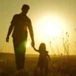 girl dad hold hands in sunset
