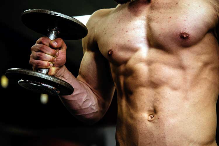 man with ripped abs lifts dumbbell at home gym