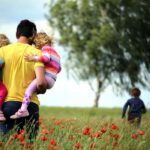 Man carrying children across field on Father's Day