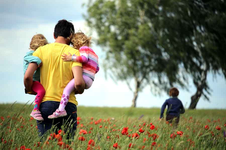 Man carrying children across field on Father's Day