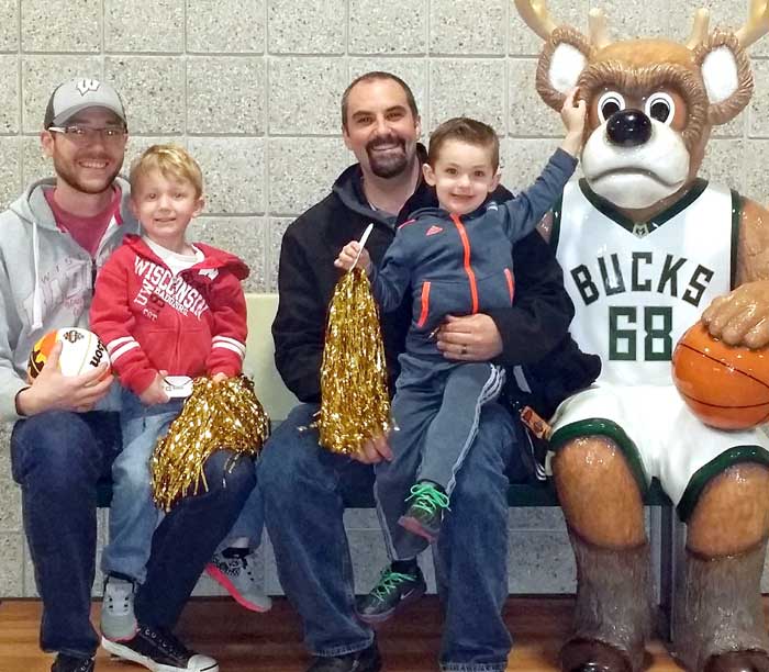 Eric Jacobs. left, of the Madison Dads Group, Pat Jacobs of the Chicago Dads Group, and their sons at a recent March Madness game in Milwaukee. (Contributed photo)