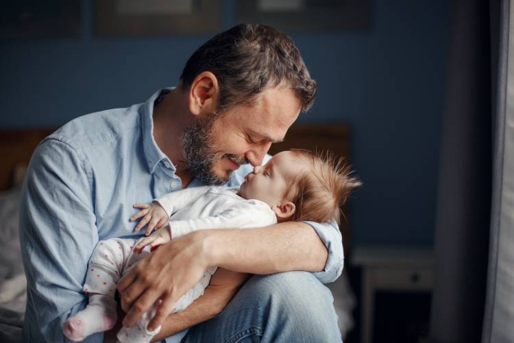 paternity leave father holds kisses baby 1