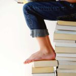 person on stack of books reading