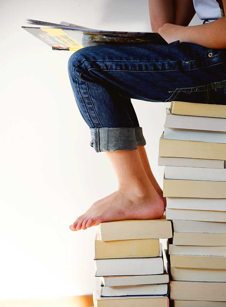 person on stack of books reading