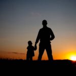presence over presents silhouette of father and son holding hands at sunset