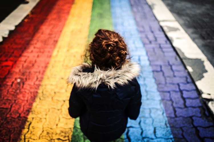 child standing on rainbow chalk pather gender experience LGBTQ