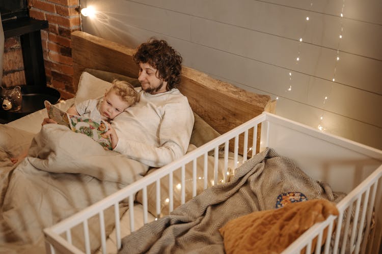 story of fatherhood dad father reading to baby child crib