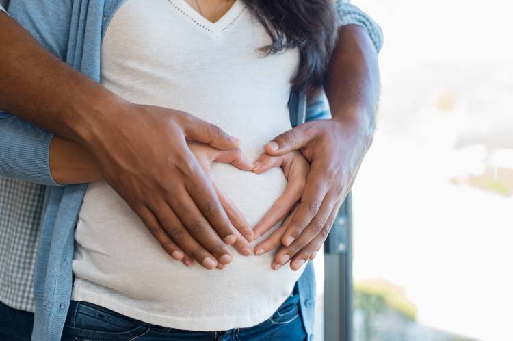 support pregnant partner man iwth hands on woman belly making heart