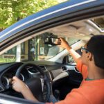 teen driver driving adjusting rearview mirror