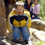 boy throws temper tantrum fit on rock