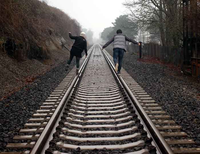 friends balance on railroad tracks trains