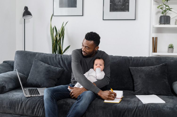 work from home dad with baby laptop on couch